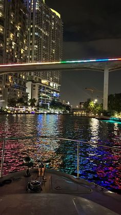 a boat traveling down a river at night with lights on the bridge and buildings in the background