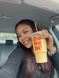 a woman sitting in the back seat of a car holding up a drink with a straw