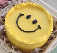 a yellow cake with a smiley face drawn on it's side in a box