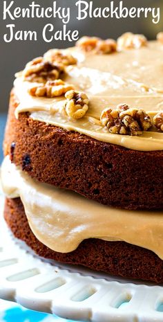 a close up of a cake with frosting and walnuts on top, sitting on a plate