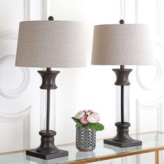 two lamps sitting on top of a table next to a vase with flowers in it