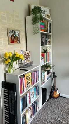 there is a book shelf with many books on it and a guitar next to it