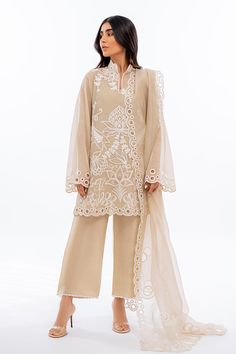 An ethereal sand coloured khaddi corduroy shirt is rendered with bold ivory dori embroidery. Eyelet details on scalloped edges are featured on the shirt as well as on the matching organza dupatta. Complete the look with our signature rawsilk culottes accented with embroidered details. Elegant Raw Silk Palazzo Set For Spring, Designer Cream Palazzo Set For Eid, Elegant Spring Raw Silk Palazzo Set, Elegant Embroidered Off White Palazzo Set, Cream Sharara With Intricate Embroidery, Beige Palazzo Set With Sheer Dupatta, Beige Palazzo Set With Dupatta, Cream Palazzo Set With Dupatta For Eid, Elegant Off-white Cotton Silk Salwar Kameez