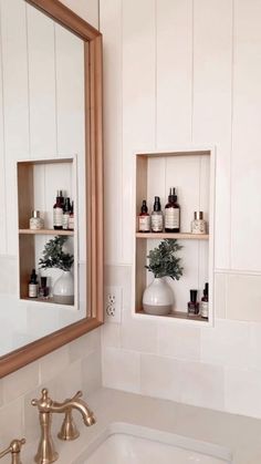 a bathroom sink sitting under a mirror next to a wall mounted shelf filled with bottles