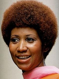 a woman with an afro is smiling for the camera