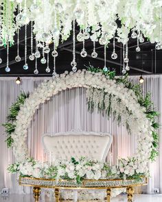 a white couch sitting under a chandelier with flowers and greenery on it