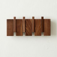 a wooden wall hanging on the side of a white wall with four pieces of wood attached to it