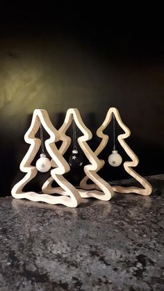 three wooden christmas trees sitting on top of a granite counter next to a black wall