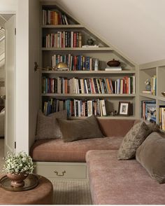 a living room filled with lots of books on top of a book shelf next to a couch