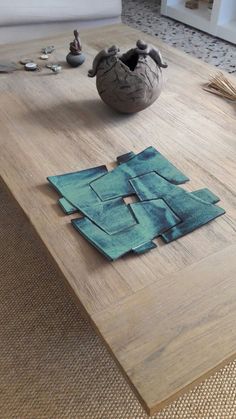 a wooden table topped with a vase on top of it next to a blue piece of cloth