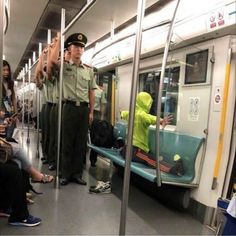 a man in uniform standing on a subway train next to people sitting and standing around