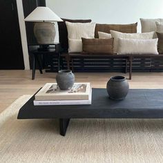 a coffee table with two vases sitting on top of it next to a couch