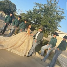 a group of people standing on the side of a road next to each other wearing green shirts and hats