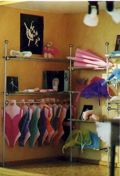 a room filled with lots of different types of clothing on shelves next to a lamp