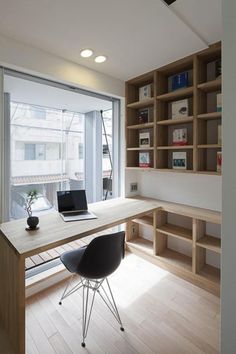 a laptop computer sitting on top of a wooden desk in front of a large window