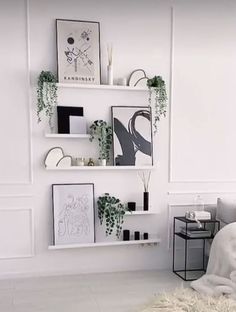 a white bedroom with plants and pictures on the wall