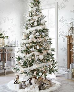 a decorated christmas tree in the corner of a living room with white and silver decor