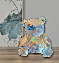 a glass teddy bear sitting next to a painting