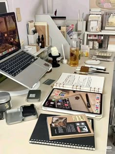 an open laptop computer sitting on top of a desk next to papers and other items