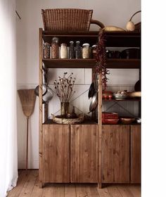 a wooden shelf filled with lots of food on top of a hard wood floor next to a white wall