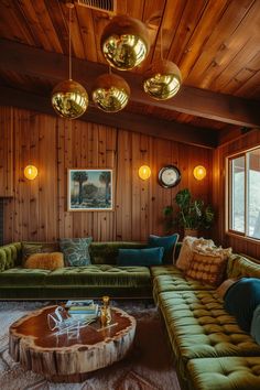 a living room filled with green couches and gold lamps hanging from the wooden ceiling