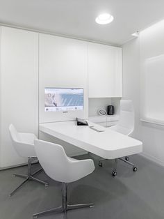 a white desk with two chairs and a computer monitor on it in an office setting