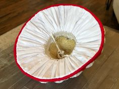 a stuffed animal inside of a white and red basket on top of a wooden table