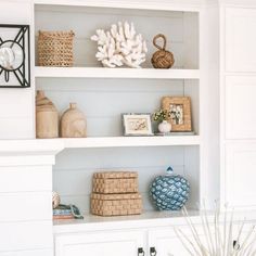 a white shelf with baskets and vases on it