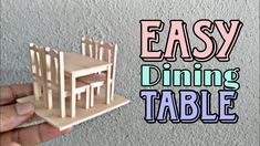 a hand holding a wooden table with chairs on it and the words easy dining table