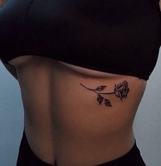 a woman's stomach with a rose tattoo on her lower side ribcage