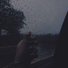 a person holding their hand out the window on a rainy day