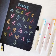 an open notebook with writing on it next to markers and pens