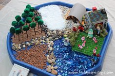 a blue tray filled with rocks, gravel and small toy houses on top of it