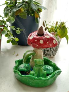 there is a small mushroom on top of a green plant in front of a potted plant