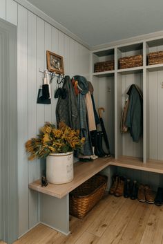 a wooden bench sitting next to a white shelf filled with shoes and flowers on top of it