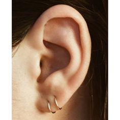 a woman's ear is shown with two small hoops on the side of her ear