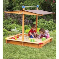 two children playing in a sandbox on the grass