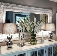 a vase filled with white flowers sitting on top of a table next to a mirror