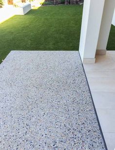 an outdoor area with grass and rocks on the ground, next to a white building