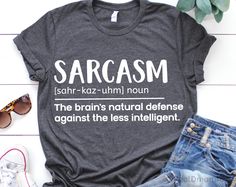 a t - shirt that says sarcasm on it next to some jeans and sunglasses