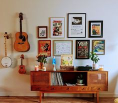 a room with guitars, posters and other items on the wall behind a wooden cabinet