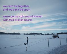 a truck driving down a snow covered road next to a wire fence with words written on it