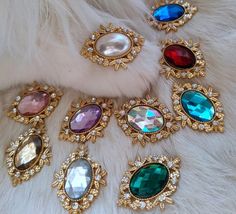 several different colored stones and jewels on a fur covered surface in gold, green, red, blue, and white colors