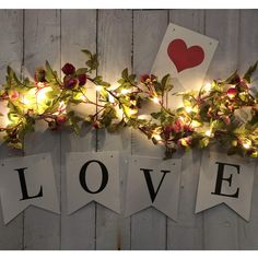 the love sign is decorated with lights and greenery, along with cards that spell out i love