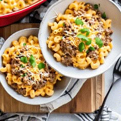 two bowls filled with macaroni and cheese on top of a cutting board