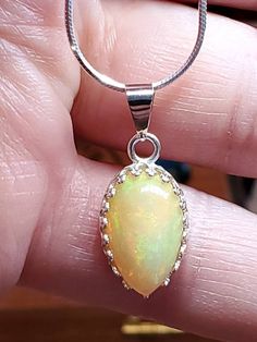 "4.00 carat green, yellow and orange natural Ethiopian opal in a Lacey bezel silver setting on a silver 18 inch chain. 5/8\" x 7/16 is the size of the stone,I will make a chain any length you like." Opal Gemstone Round Pendant Necklace, White Gold Opal Necklace As Gift, White Gold Opal Necklace For Gift, White Gold Opal Round Necklace, Opal Gemstone Round Pendant Jewelry, Opal Teardrop Pendant Necklace With Gemstone, Amber Sterling Silver Necklace With Cabochon, Amber Cabochon Necklace In Sterling Silver, Amber Cabochon Necklaces In Sterling Silver