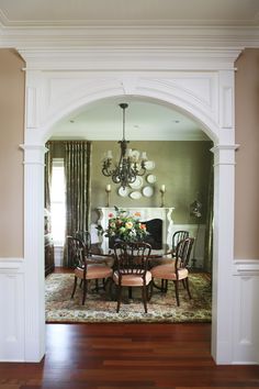 an archway leads into a formal dining room with wood floors and white trim on the walls