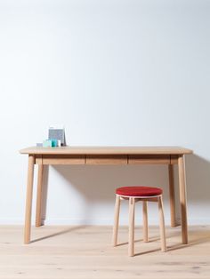 a wooden desk with a red stool next to it