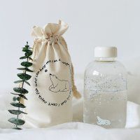 a bottle and bag sitting next to each other on a white surface with trees in the background