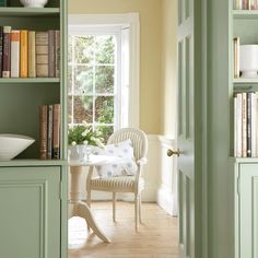 a room with green bookshelves and white dishes on top of the shelves in it